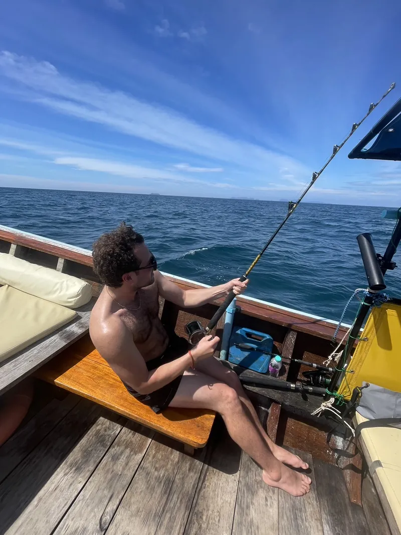 Guest reeling in with a rod from the back of a longtail